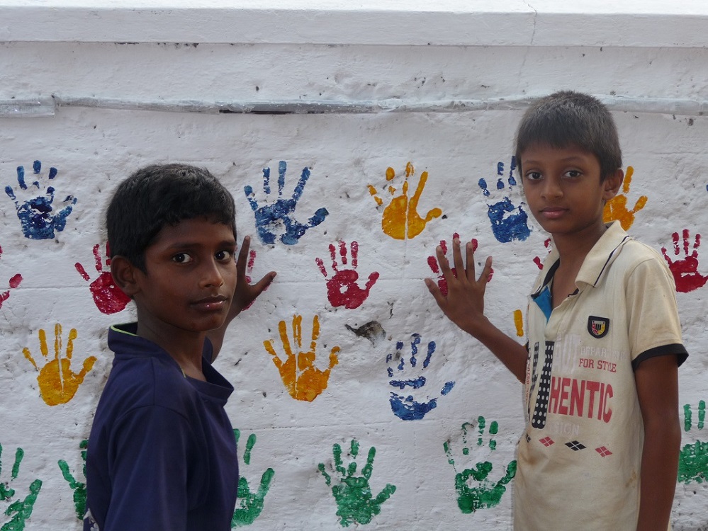 Dilip und Santosh mit den fertigen Handabdrücken auf der Mauer. (Foto: EMS/Schupp) Dilip und Santosh mit den fertigen Handabdrücken auf der Mauer. (Foto: EMS/Schupp)
