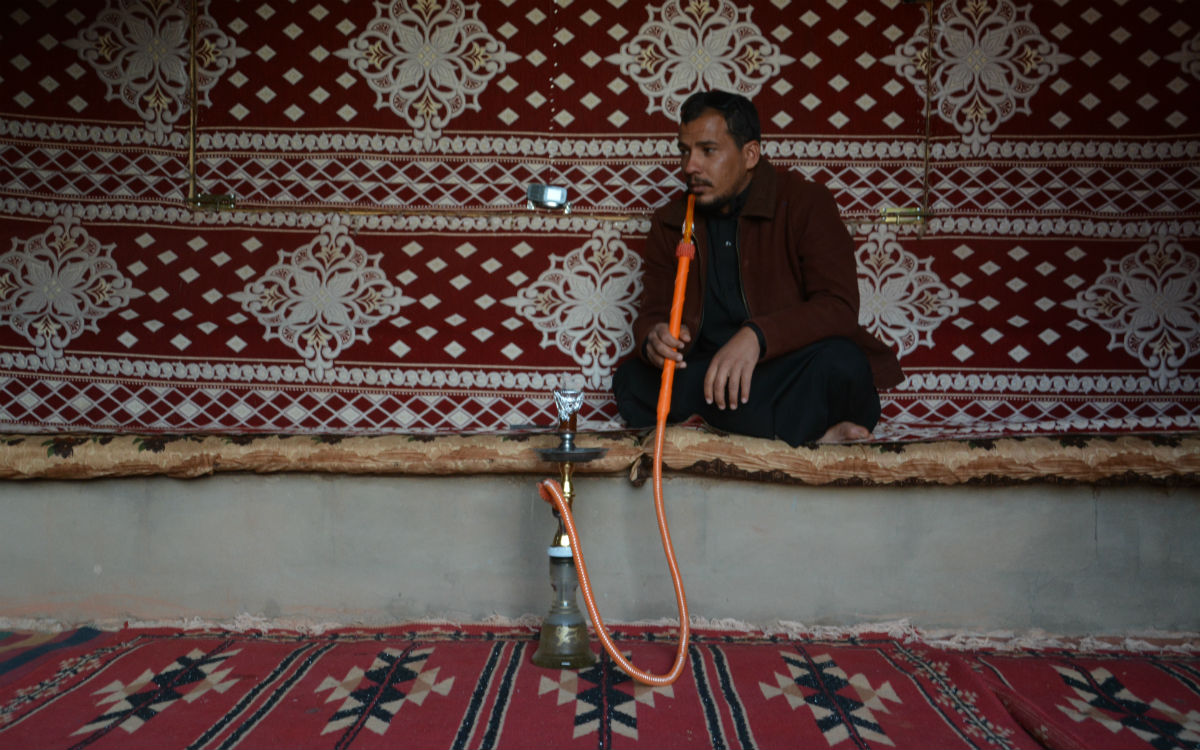 Ibraheem im Gemeinschaftszelt während er eine Shisha raucht (Foto: ems/Schnotz)